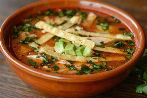 Sopa de tortilla servida en un tazón tradicional con guarniciones
