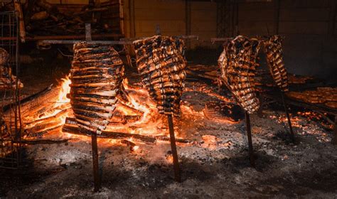Esquema de un asado a la estaca con animal en cruz frente a brasas