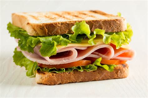 Sándwich fresco de jamón, queso, lechuga y tomate servido en un plato