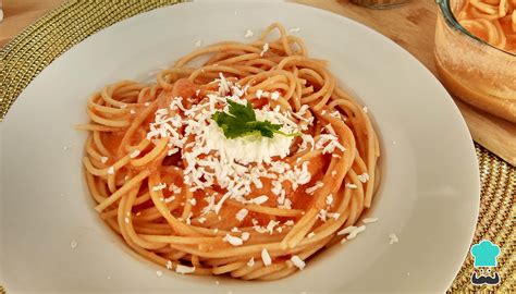 Plato de espagueti rojo con crema servido con queso y perejil