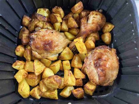 Muslos de pollo en freidora de aire servidos con patatas y ensalada