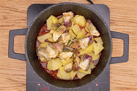 Patatas y alcachofas añadiéndose al guiso