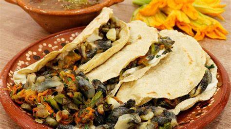 Ingredientes frescos: flor de calabaza, huitlacoche y chiles poblanos sobre una mesa de madera