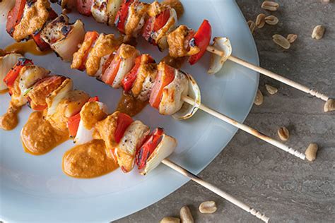 brochetas de pollo servidas con salsa de cacahuete
