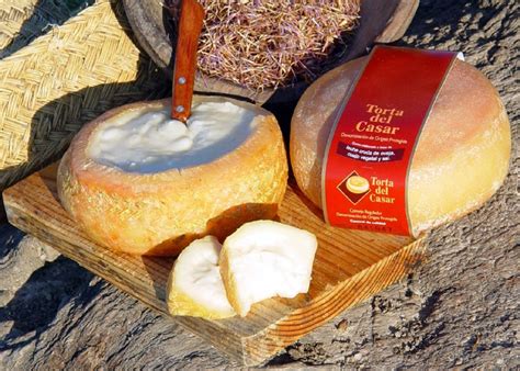 Torta del Casar sobre una tabla de madera con pan y vino