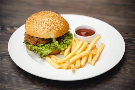 Hamburguesa vegetal en un plato con patatas fritas y ensalada