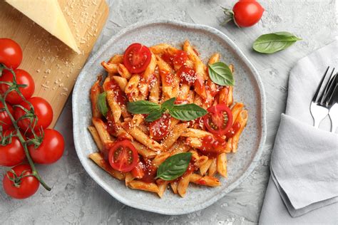 Pasta servida en plato hondo con vegetales decorativos