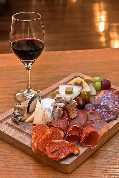 Copas de vino tinto junto a una tabla de embutidos