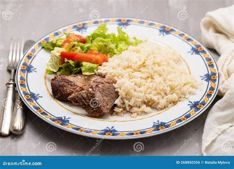 Plato de carne asada servido con guarnición de ensalada y arroz