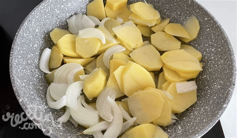Patatas cortadas finamente y cebolla pochándose en una sartén