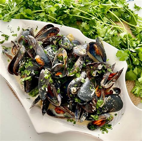 Mejillones con lima y coco cocinándose en una olla sobre la parrilla
