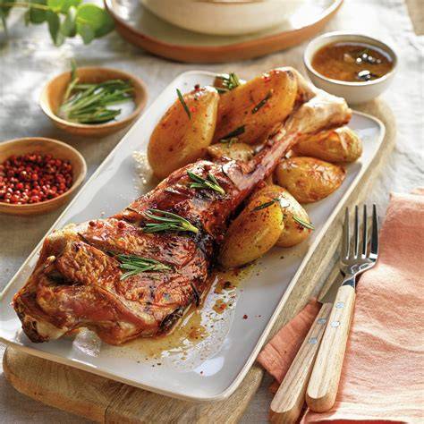 Plato servido de cordero asado con patatas y ensalada
