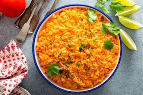Plato de arroz rojo servido como guarnición junto a carne asada