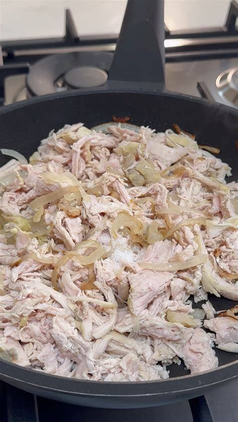Pollo desmechado cocinándose en una sartén con verduras