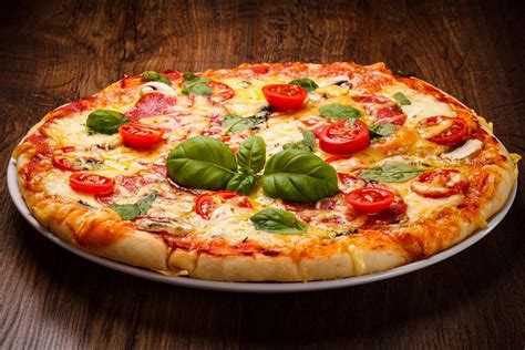 Pizza Napolitana clásica redonda con borde grueso y burbujeante, tomate, mozzarella y albahaca