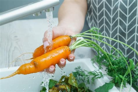 Una persona lavando zanahorias bajo un chorro de agua