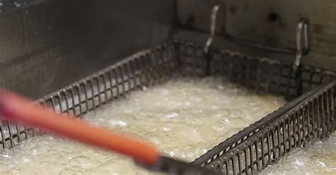 Chef friendo alimentos en una freidora comercial