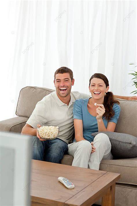Pareja sonriente disfrutando palomitas caseras en un sofá