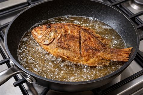 Tilapia friéndose en una sartén con aceite caliente