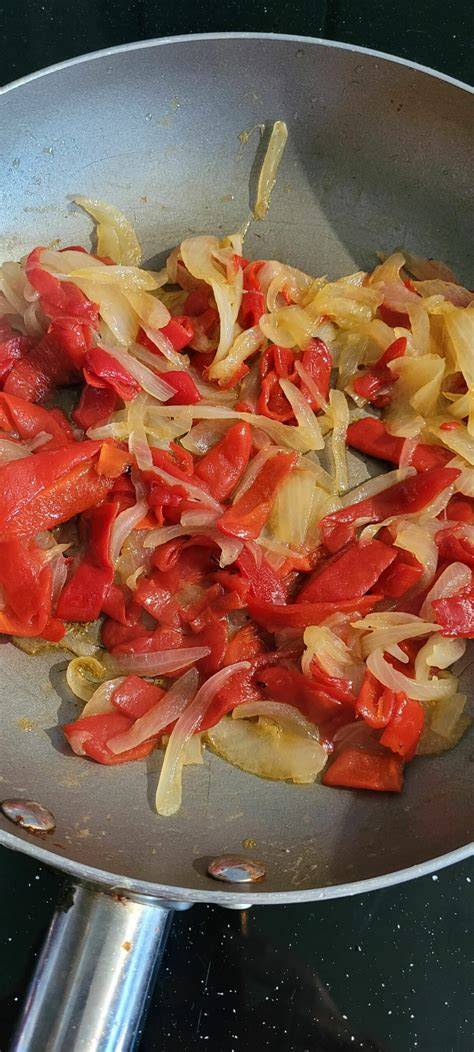 Cebolla y pimiento rojo salteándose en una sartén