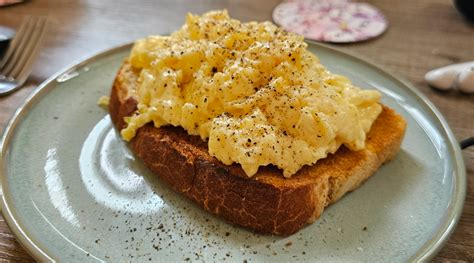Tostada de pan integral con huevos revueltos y brotes