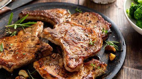 Chuletas de cerdo dorándose en una sartén caliente