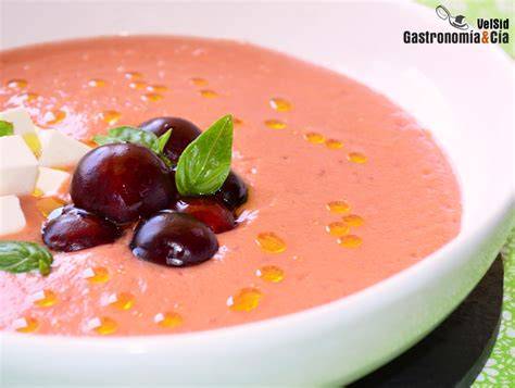 Plato de gazpacho de cerezas decorado con queso feta y albahaca