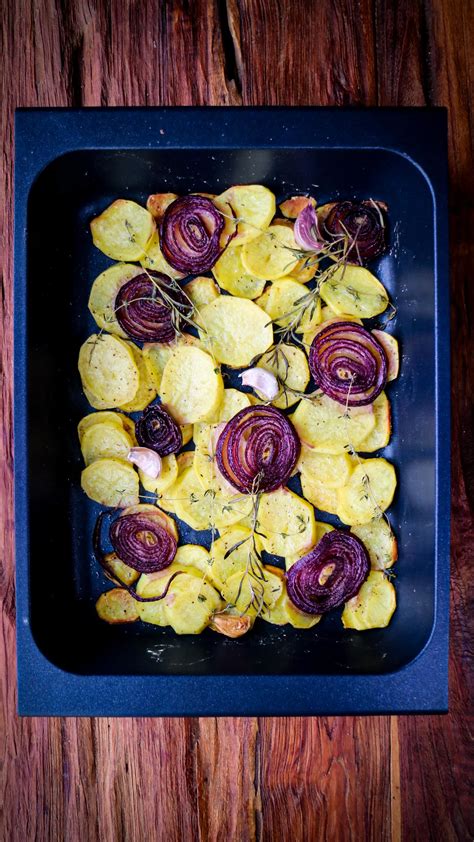 Cama de patatas, cebolla y ajos en bandeja de horno