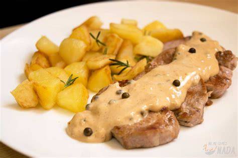 Plato de solomillo a la pimienta verde con guarnición de patatas asadas