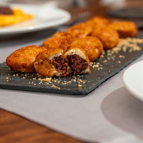 Plato de croquetas de patata rellenas de morcilla y cebolla confitada