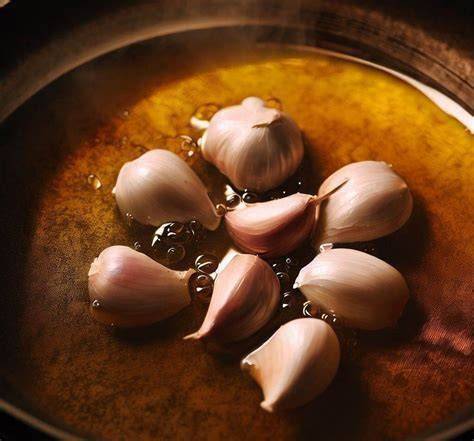 Ajos y guindillas confitándose en aceite de oliva