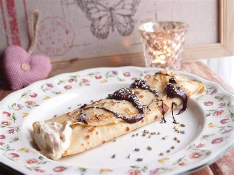 Crepes rellenos de mousse de turrón decorados con sirope de chocolate y azúcar glass
