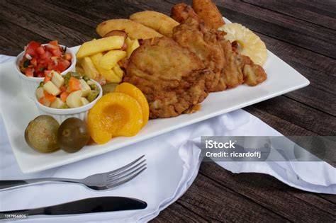 Bistec empanado servido con limón y patatas