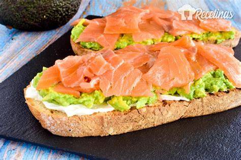 Primer plano de una tosta de salmón con aguacate y albahaca
