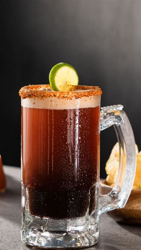 Vaso de michelada mexicana con espuma y rodajas de limón