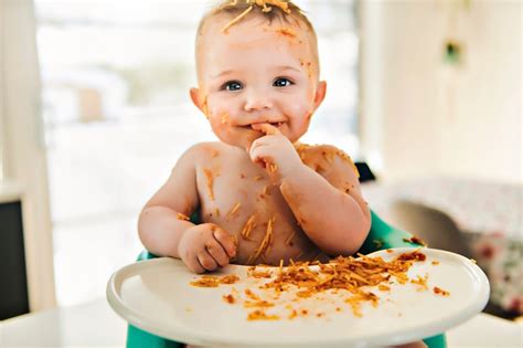 Bebé comiendo trozos de comida con sus manos