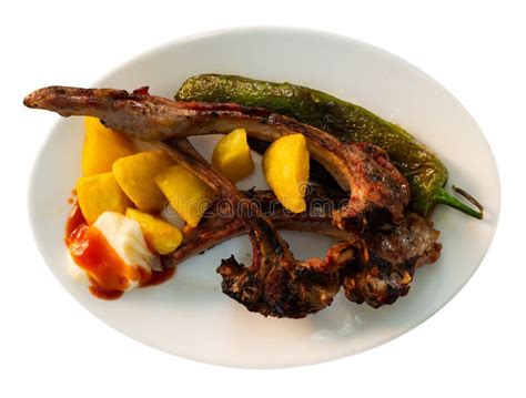 costillas fritas servidas con guarnición de patatas y pimientos
