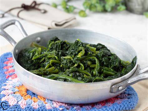 Espinacas frescas salteándose en una sartén con ajo y cebolla