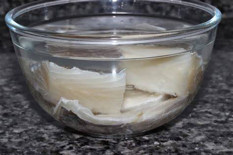 Bacalao en remojo en un recipiente con agua en el frigorífico