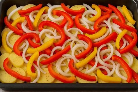 Bandeja con patatas, cebolla y otras verduras listas para hornear