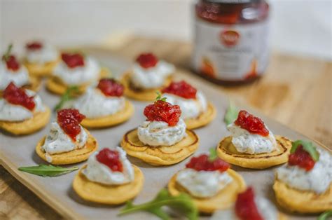 Primer plano de blinis con queso crema, mermelada y nueces