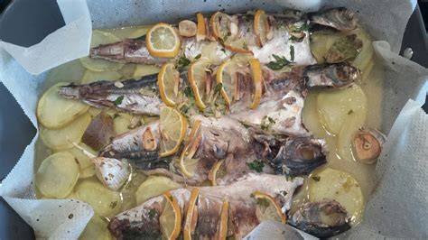 Imagen de un chicharro al horno recién hecho con patatas