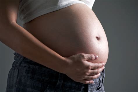 Fotografía de una barriga de embarazada en el sexto mes comparada con una calabaza