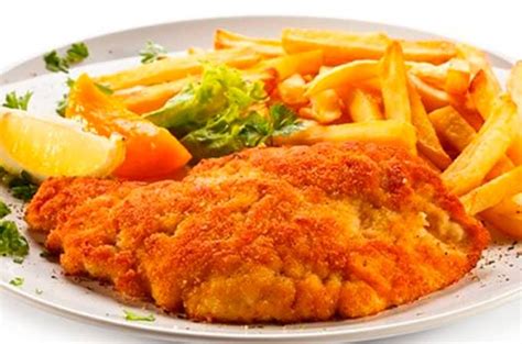 Chuleta de cerdo apanada en un plato con guarniciones