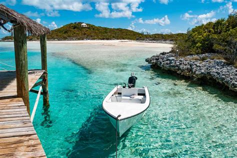 Barco navegando por las aguas cristalinas de Exuma con pequeñas islas en el horizonte