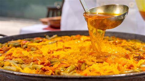Proceso de añadir caldo y especias a la paella