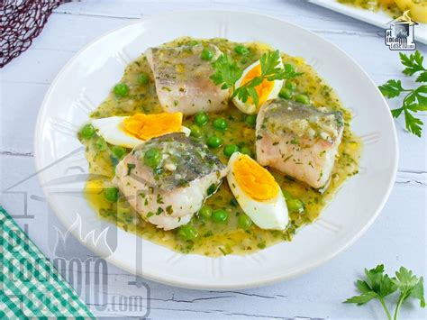 Merluza en salsa verde servida con huevo duro y espárragos