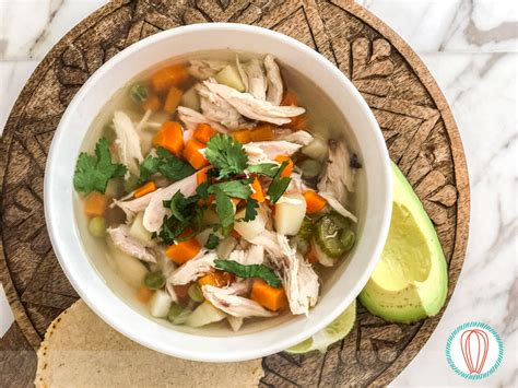 Tazón humeante de caldo de pollo vegano con verduras y aguacate