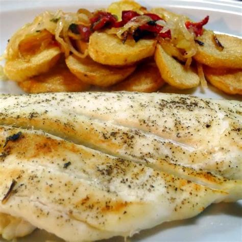Plato de lenguado al horno con rodajas de limón y patatas doradas