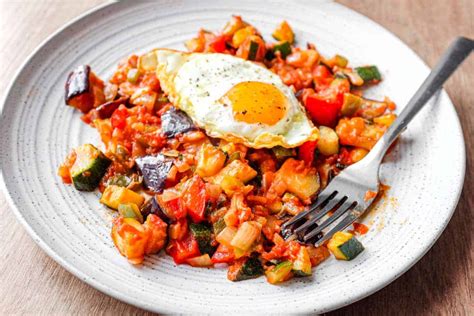 Plato de pisto de berenjena y calabacín servido con huevo frito